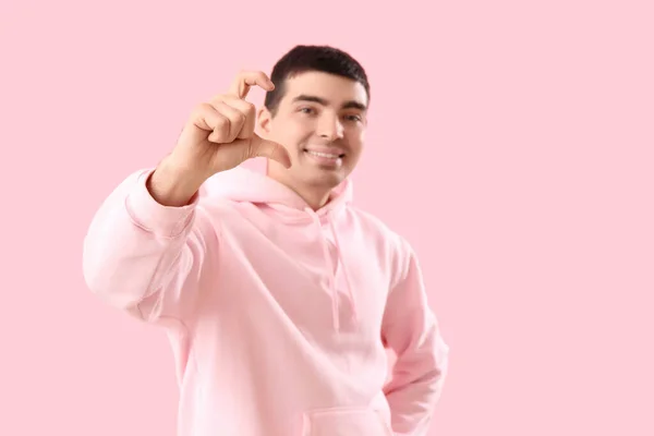 ピンクの背景に指で心を作る若い男 — ストック写真