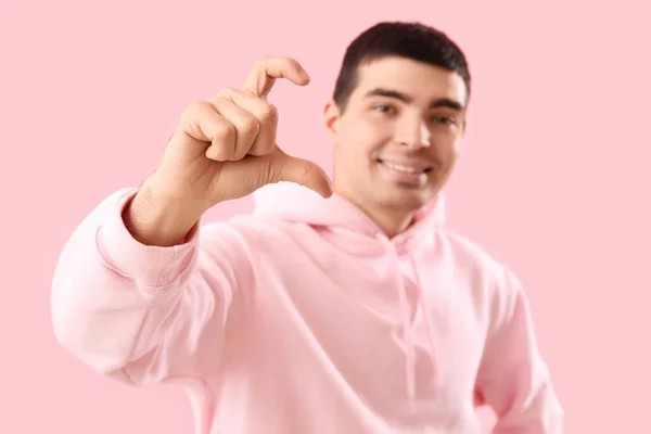 ピンクの背景に指で心臓を作ってる若い男が — ストック写真