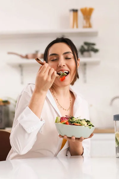 台所で野菜サラダを食べる若い女性 — ストック写真