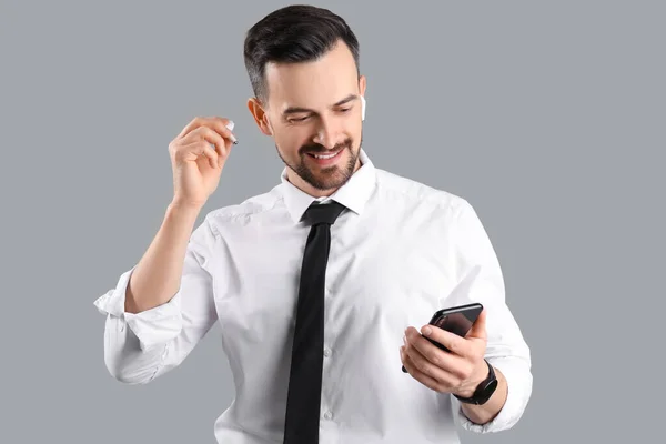 Bonito Homem Negócios Fones Ouvido Usando Telefone Celular Fundo Cinza — Fotografia de Stock