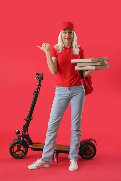 Зрілий Кур Піцою Електричним Велосипедом Вказує Щось Червоному Тлі — стокове фото