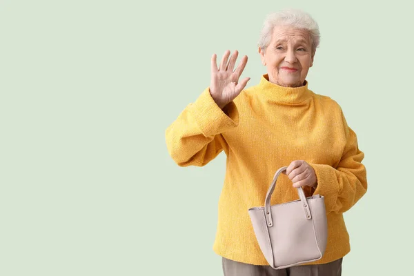 Senior Kvinna Med Väska Viftande Hand Grön Bakgrund — Stockfoto