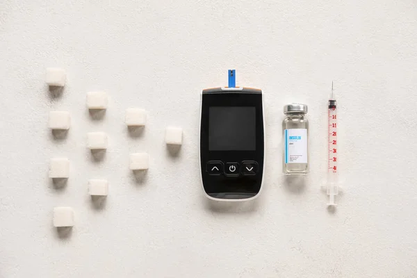 Glucometer with insulin, syringe and sugar on white background. Diabetes concept