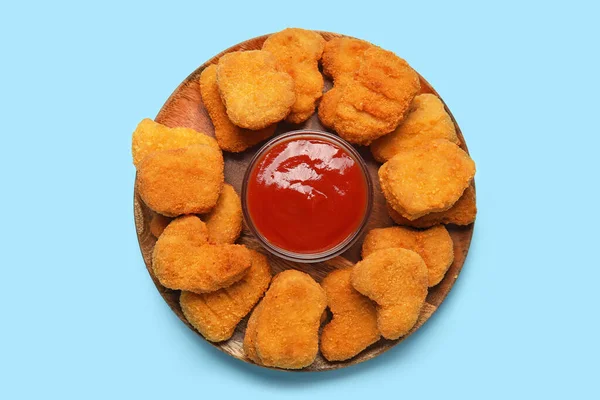 Plate of tasty nuggets with ketchup on blue background