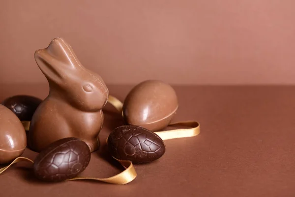 チョコレートイースターエッグ ウサギとリボンの茶色の背景 — ストック写真