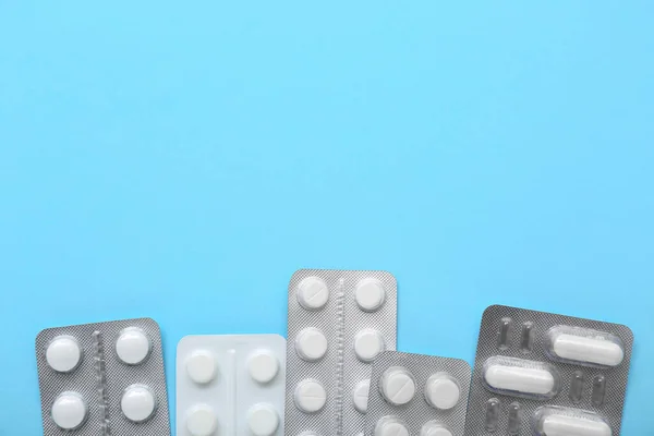 Blisters of pills on blue background, closeup