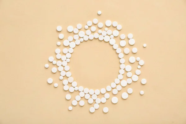 Frame made of white pills on beige background
