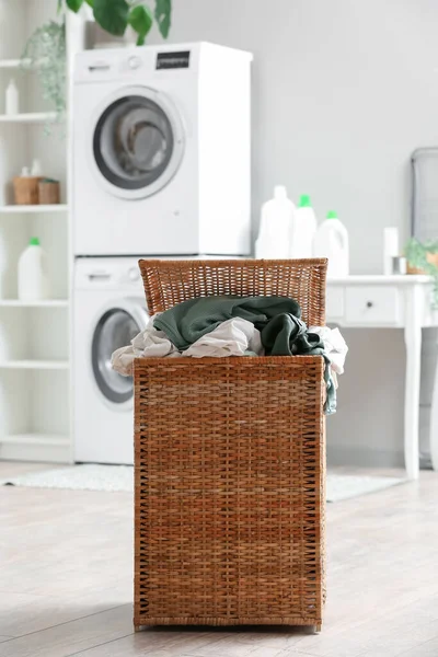 Basket with dirty clothes in laundry room