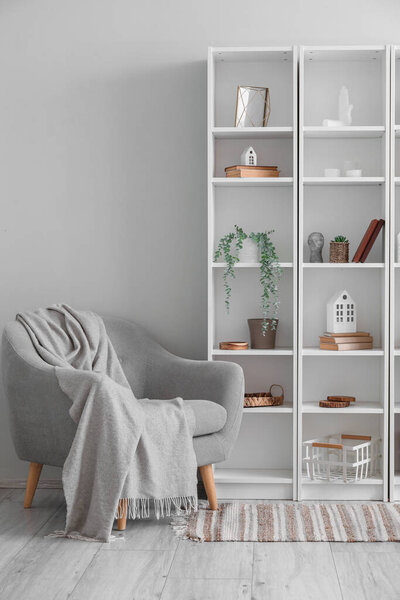 Interior of living room with armchair, shelving unit and artificial plants