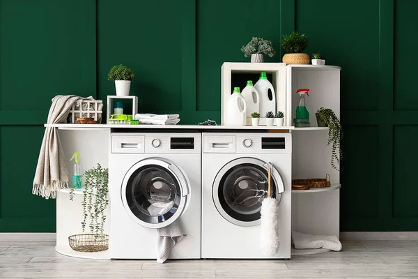 Interior of laundry room with washing machines, shelving units and artificial plants