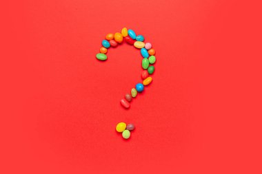 Kırmızı arkaplandaki şekerlerden oluşan soru işareti