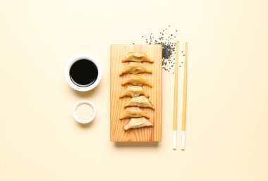 Lezzetli Çin jiaozi 'li ahşap tahta, susam ve bej arka planda sos.