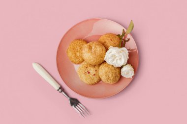 Pembe arka planda lezzetli choux tatlılı tabak.