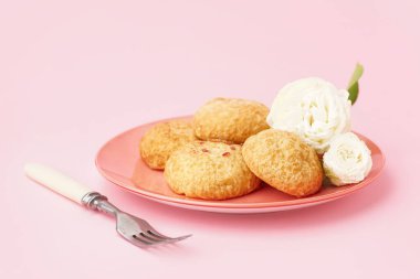 Pembe arka planda lezzetli choux tatlılı tabak.