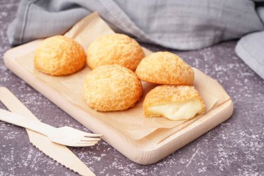 Arkaplanda lezzetli choux tatlısıyla ahşap tahta.