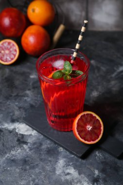 Bir bardak koyu arkaplanda kan portakallı limonata.