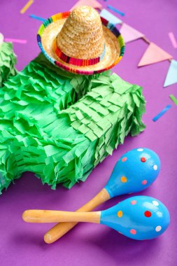 Meksika marakadaları pinata, sombrero şapkası, kağıt bayraklar ve mor arka planda konfeti, yakın plan.