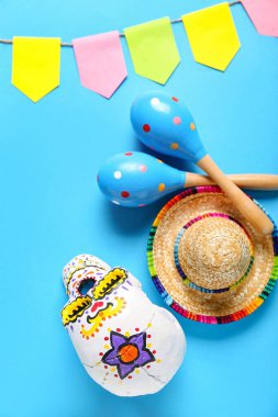 Meksika marakas şapkası, boyalı kafatası ve mavi arka planda bayraklar