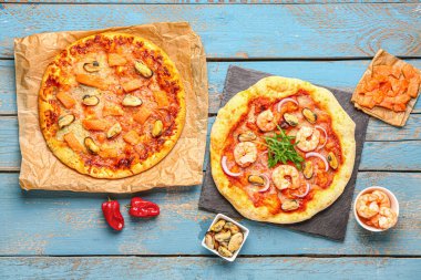 Mavi ahşap arka planda lezzetli deniz ürünleri pizzaları.