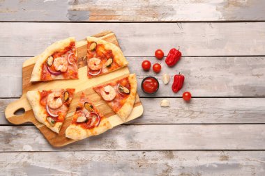 Hafif ahşap arka planda lezzetli deniz ürünleri pizzası.