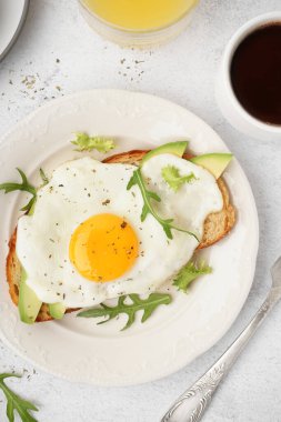 Hafif arka planda kızarmış yumurta, roka ve avokado ile nefis sandviç.