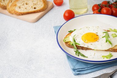 Hafif arka planda kızarmış yumurta, avokado ve roka ile nefis sandviç.