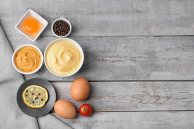 Lezzetli mayonez soslu kase ve hafif ahşap arka planda malzemeler.