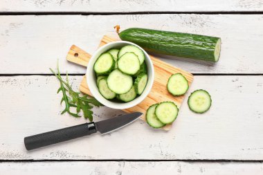 Hafif ahşap arka planda taze kesilmiş salatalık kasesi.