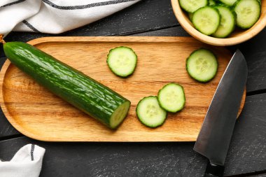 Koyu ahşap arka planda taze kesilmiş salatalıklı tahta.