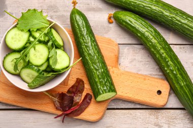 Hafif ahşap arka planda taze kesilmiş salatalık kasesi.