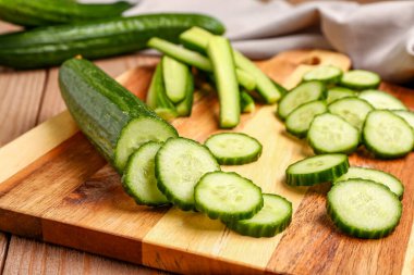 Ahşap arka planda taze kesilmiş salatalıklı tahta, yakın plan.