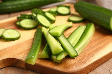 Ahşap arka planda taze kesilmiş salatalıklı tahta, yakın plan.