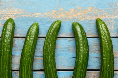 Mavi ahşap arka planda taze salatalıklar, yakın plan.