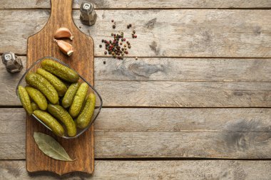 Lezzetli mayalanmış salatalık, malzemeler ve ahşap arka planda yemek kasesi.