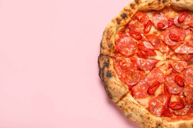 Pembe arka planda nefis biberli pizza.
