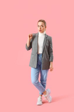 Pembe arka planda gözlüklü düşünceli genç bir iş kadını.
