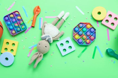 Yeşil arka planda konfeti olan bebek oyuncakları. Çocuk Bayramı kutlaması