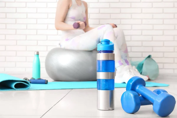 Dumbbells with sports water bottle in gym, closeup