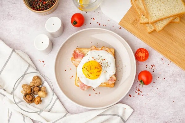 stock image Delicious sandwich with fried egg and bacon on light background