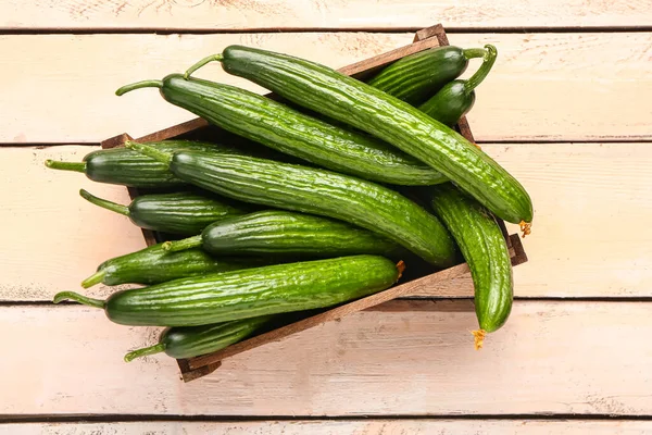 stock image Box with fresh cucumbers on light wooden background