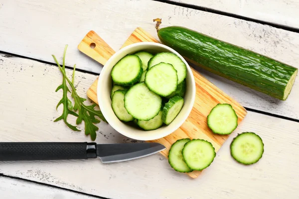 Hafif ahşap arka planda taze kesilmiş salatalık kasesi.