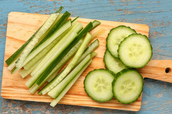 stock image Board with fresh cut cucumber on blue wooden background, closeup