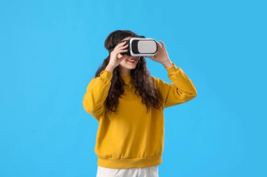 Mavi arka planda VR gözlüklü genç kız.