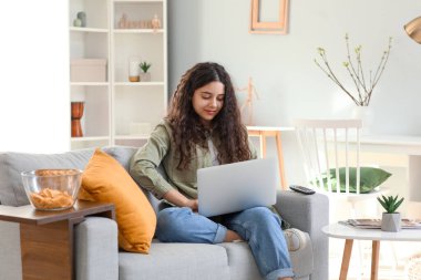 Teenage girl using laptop on sofa at home