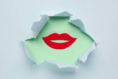 Kırmızı kağıt dudaklar mavi kağıttaki delikten görülebilir.