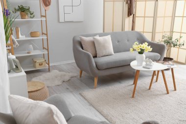 Gri kanepeli, katlanır perdeli ve masalı oturma odasının içi.