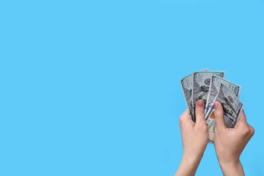 Mavi arka planda dolar banknotları olan kadın.