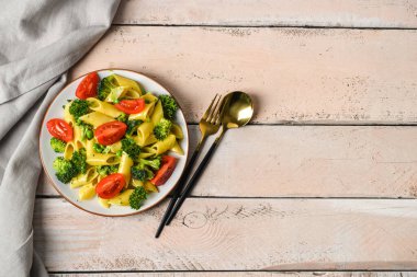 Lezzetli makarna ve açık ahşap arka planda brokoli tabağı.