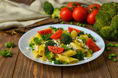 Lezzetli makarna ve ahşap arka planda sebze tabağı.