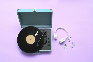 Vinil diski, kulaklığı ve eflatun arkaplanı üzerinde not tabelaları olan kayıt çalar